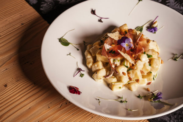 Gnocchi in Sahnesauce mit geräuchertem Bernardi Schinkenspeck und einem Topping aus Pinienkernen und Wildkräuern aus der Enotheque Bruneck